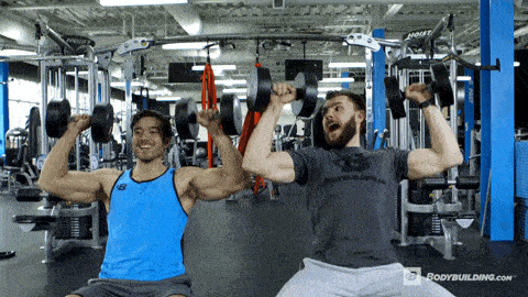 Two guys doing seated overhead press and smiling as training partners