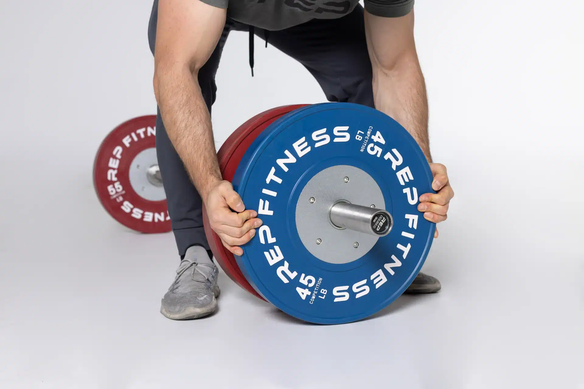 man loading rep fitness competition plates onto barbell