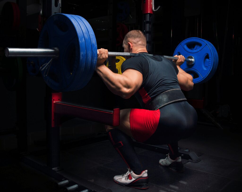 man squatting outside squat rack with safety arms