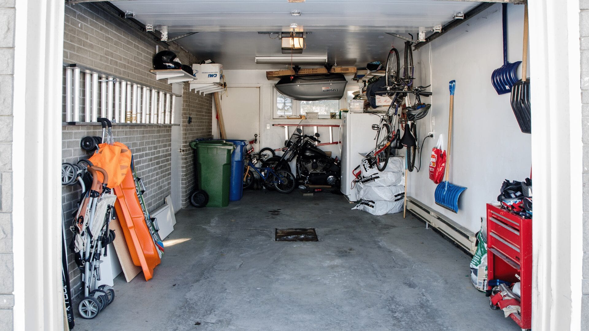 small garage with normal things like a trash can, fridge, and other storage