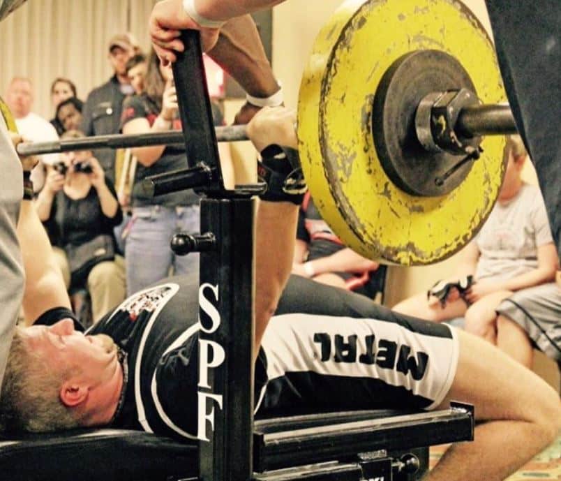 man performing the bench press in a powerlifting meet while using a power bar