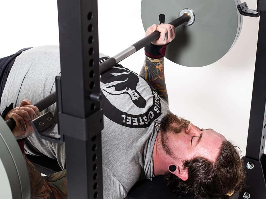 man performing the bench press with a powerlifting barbell