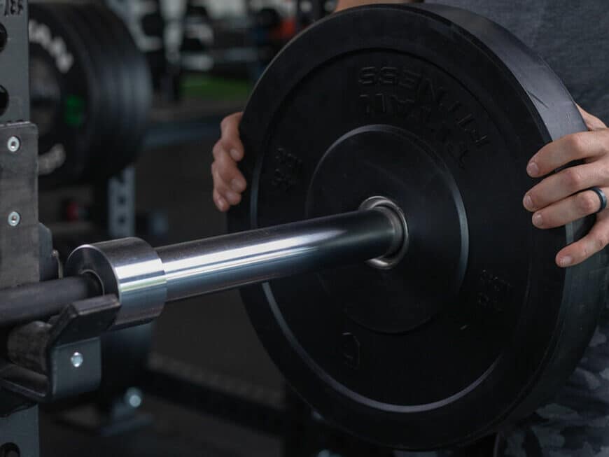 man loading a bumper plate onto barbell sleeve