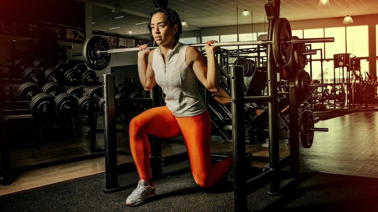 girl doing lunges in squat rack with 1" standard barbell
