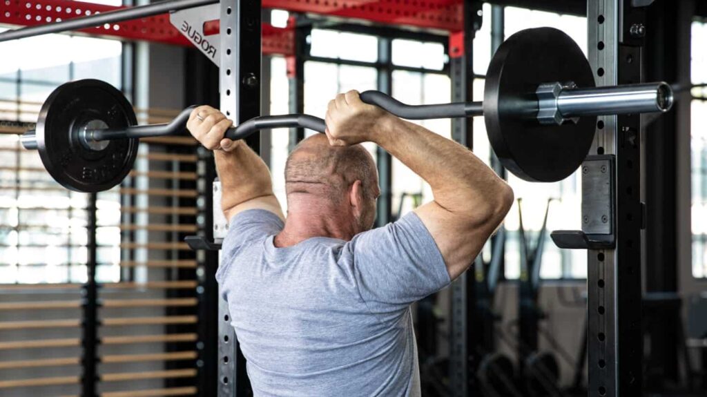man doing overhead tricep extensions with rackable curl bar