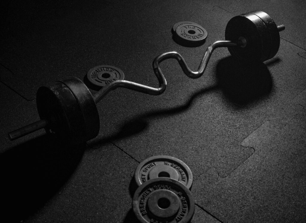 close up shot of a super curl bar showing off its angled grips with standard weight plates on the gym floor