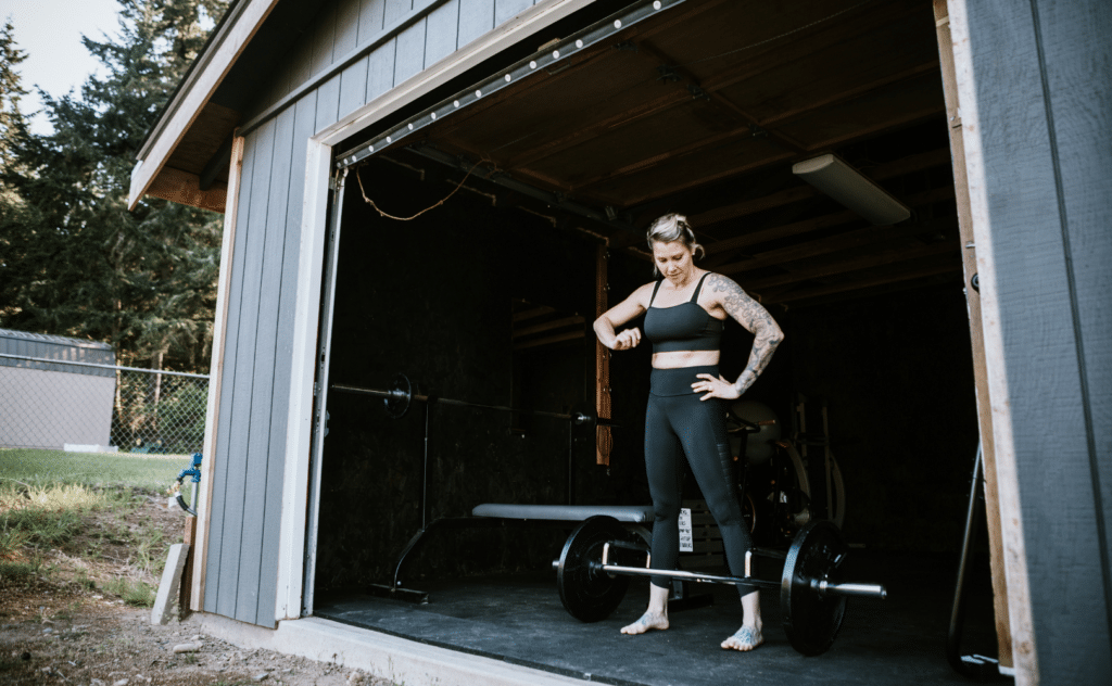 woman resting inside trap bar in her garage gym