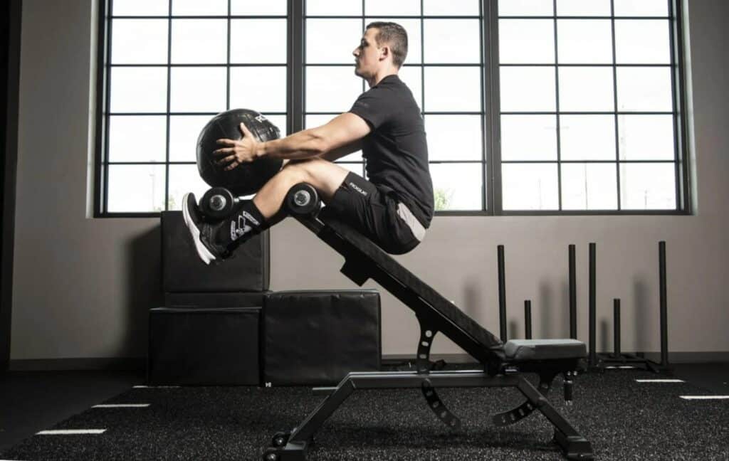 man doing situps on adjustable bench with medicine ball