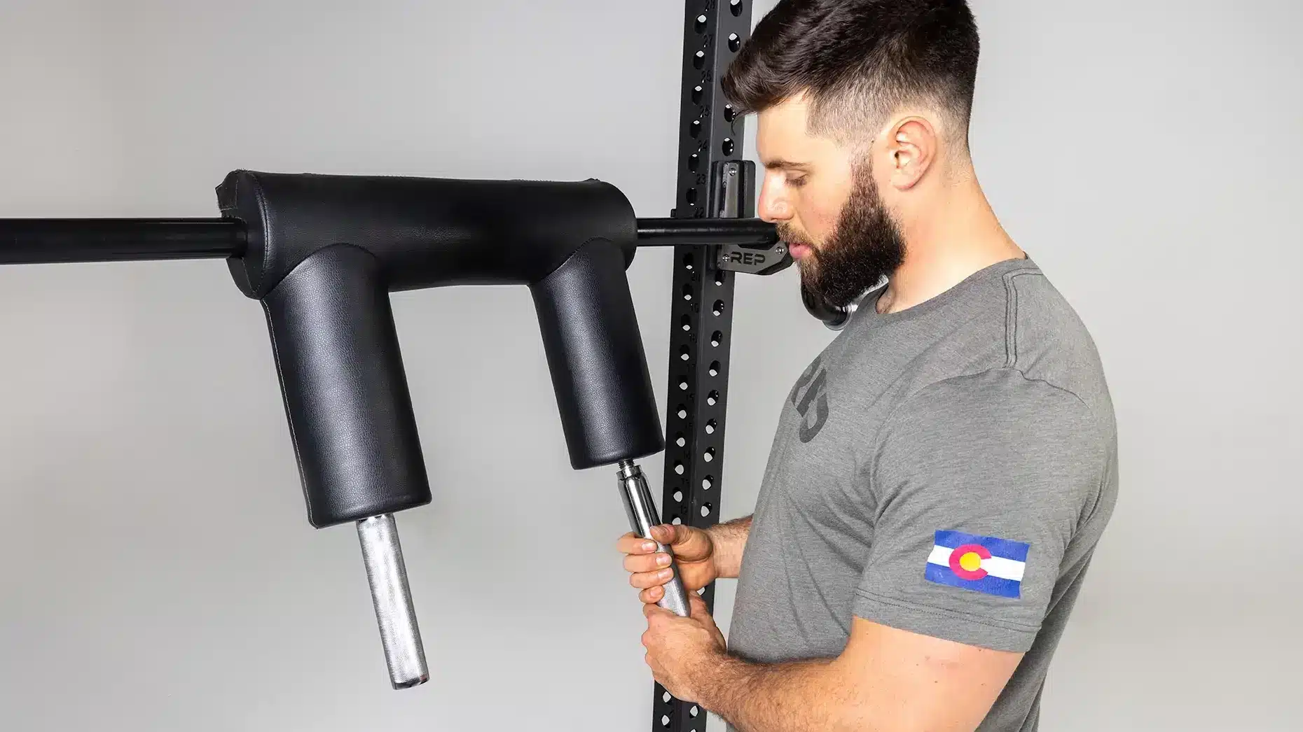 man unscrewing the knurled handles on a safety squat bar