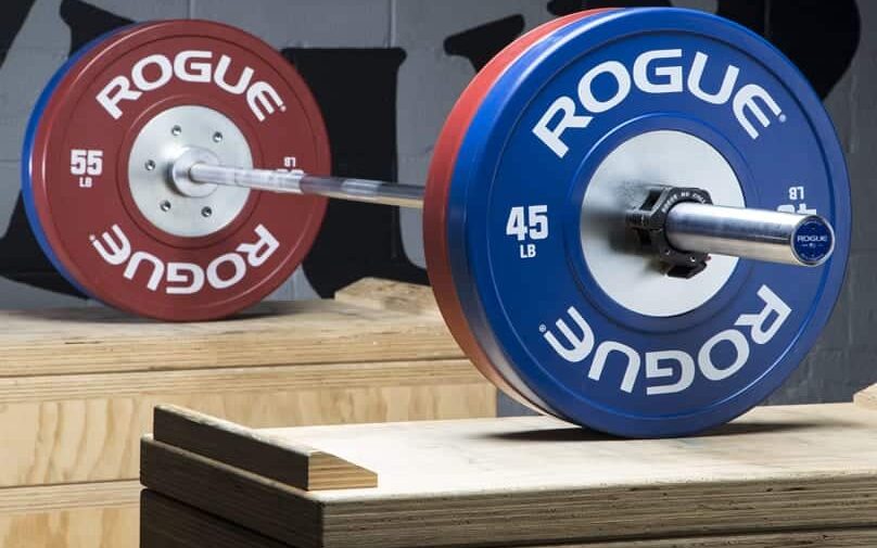 rogue training bumpers loaded onto a barbell rested on jerk blocks