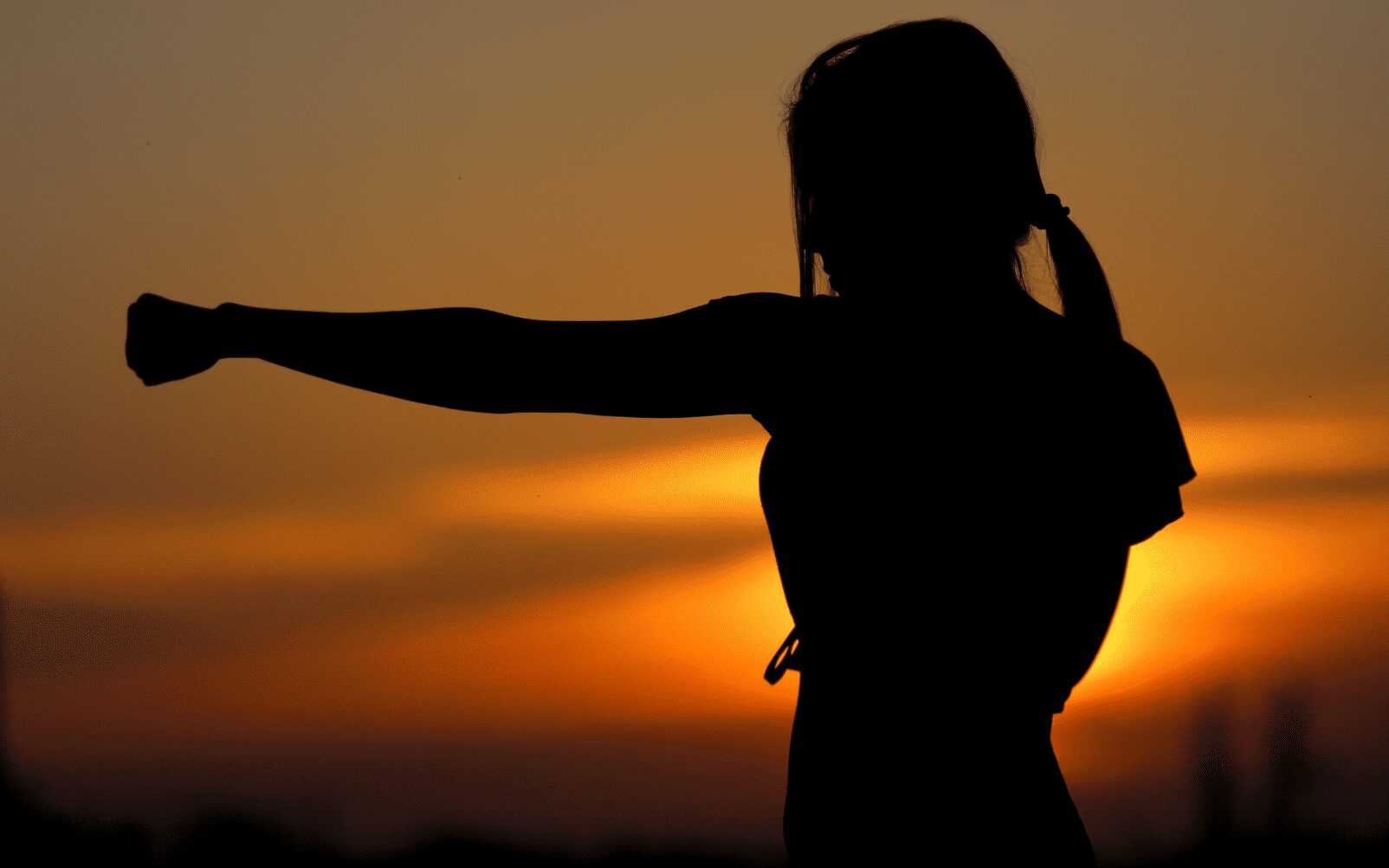 womans silhouette shown punching in front of sunset