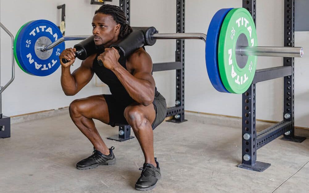 man squatting with the titan safety squat bar
