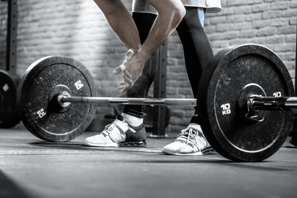 man chalking up to lift barbell with center knurl
