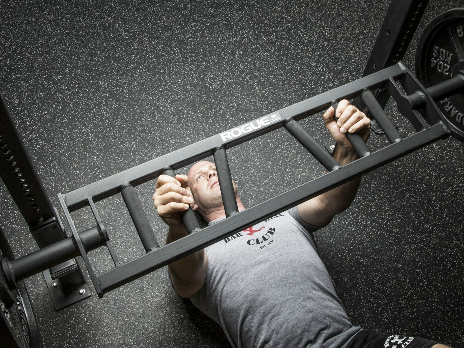 man doing floor press with rep multi-grip bar