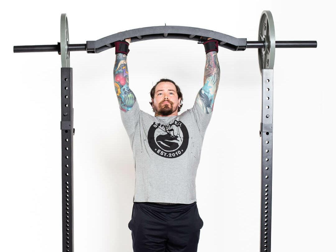 man overhead pressing with bells of steel swiss bar