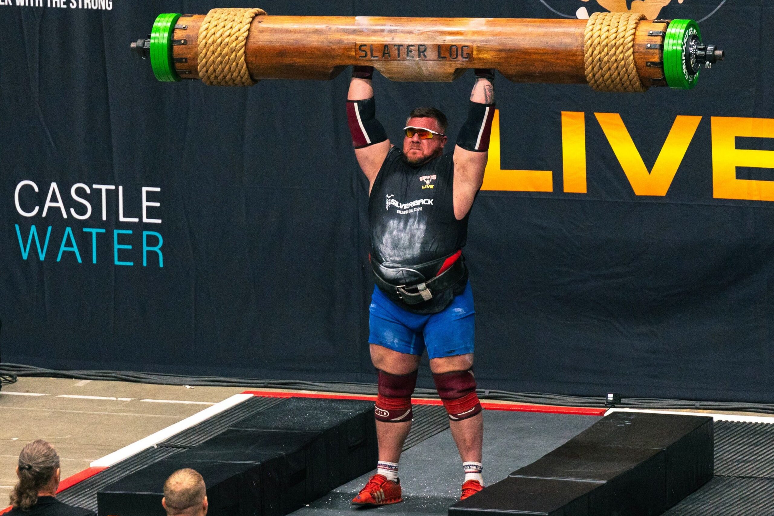 strongman doing a log press with a log barbell