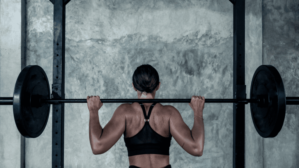 woman unracking barbell with bar on her traps