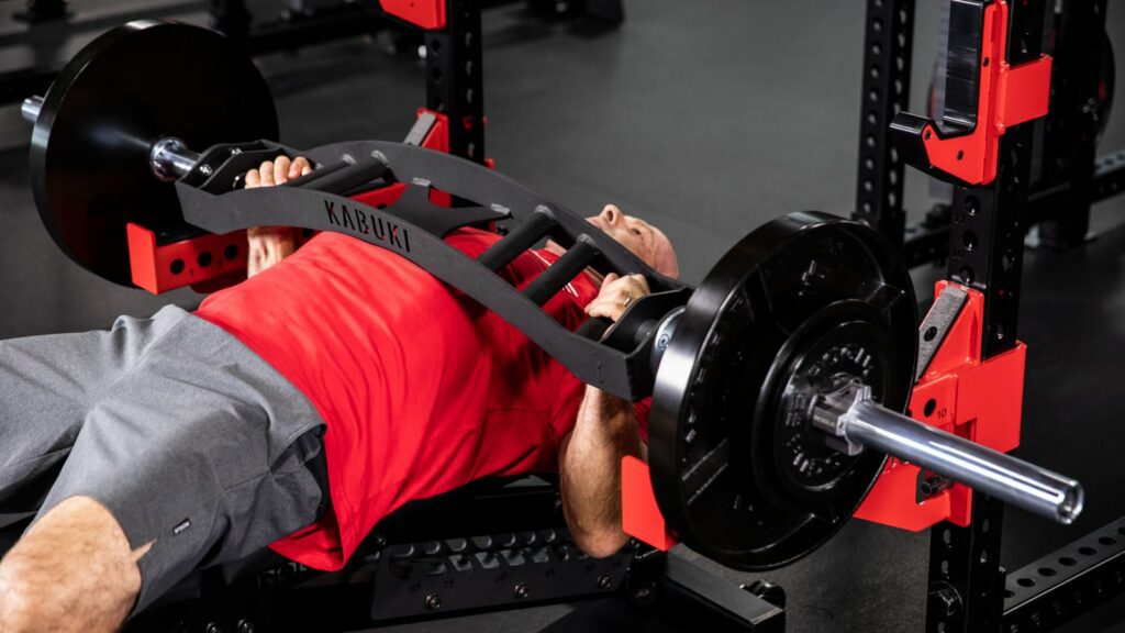 man benching with football bar