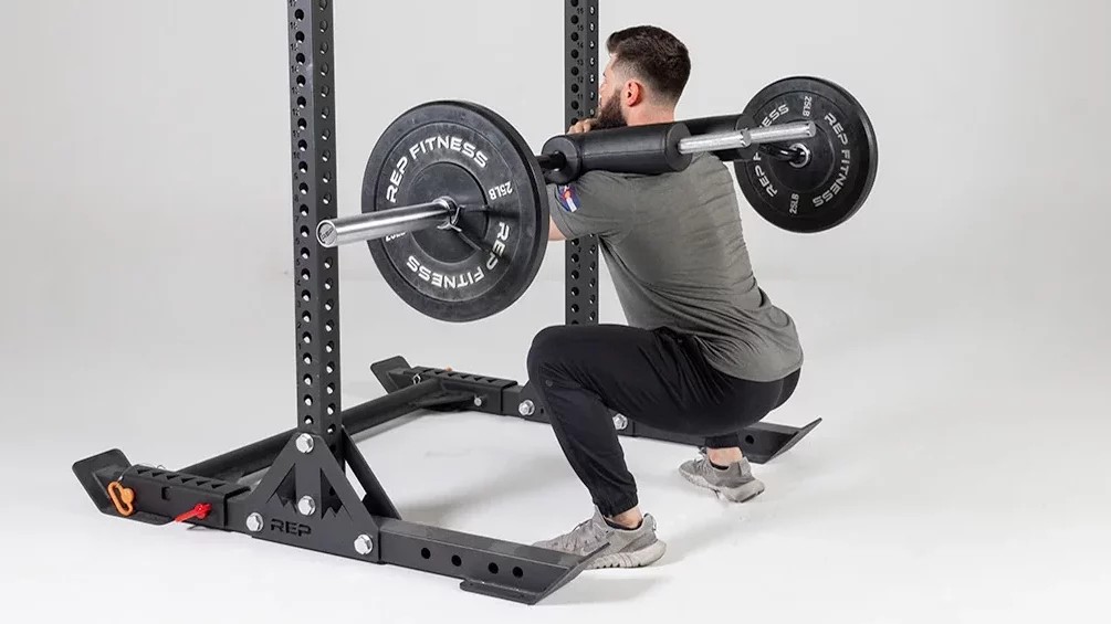 man squatting in front of half rack