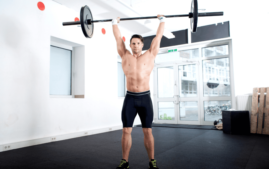 man performing the overhead press in white room