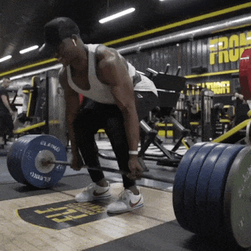 man in white tanktop doing deadlifts with bumper plates